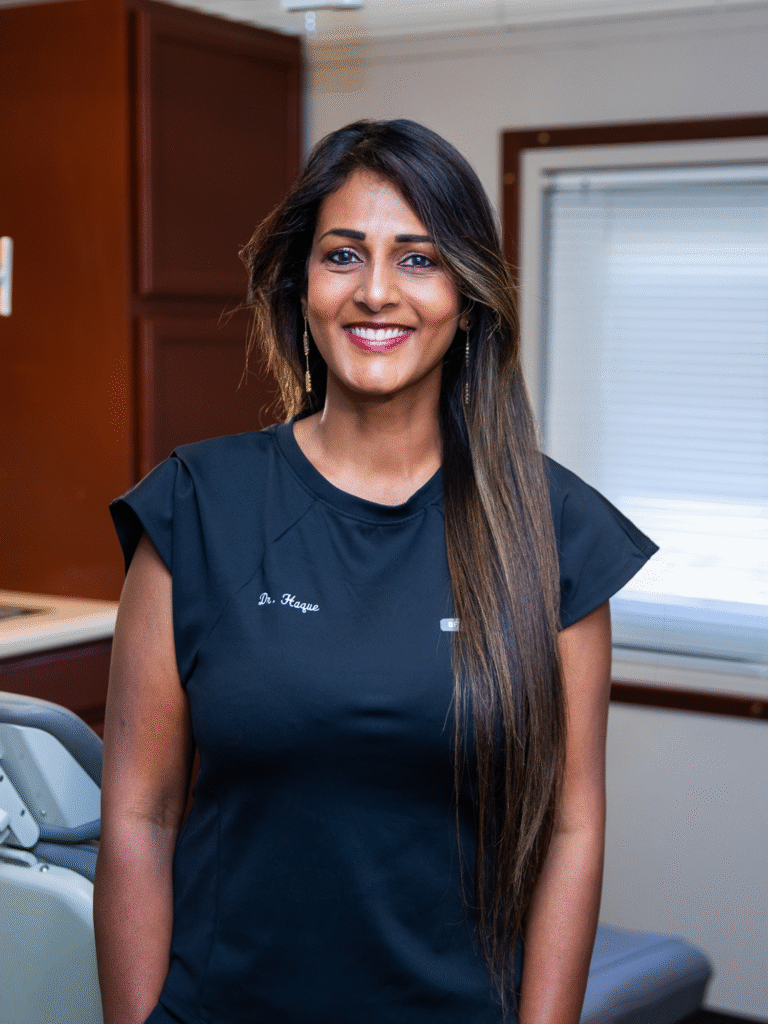 Dr. Haque smiling in her office in blue scrubs